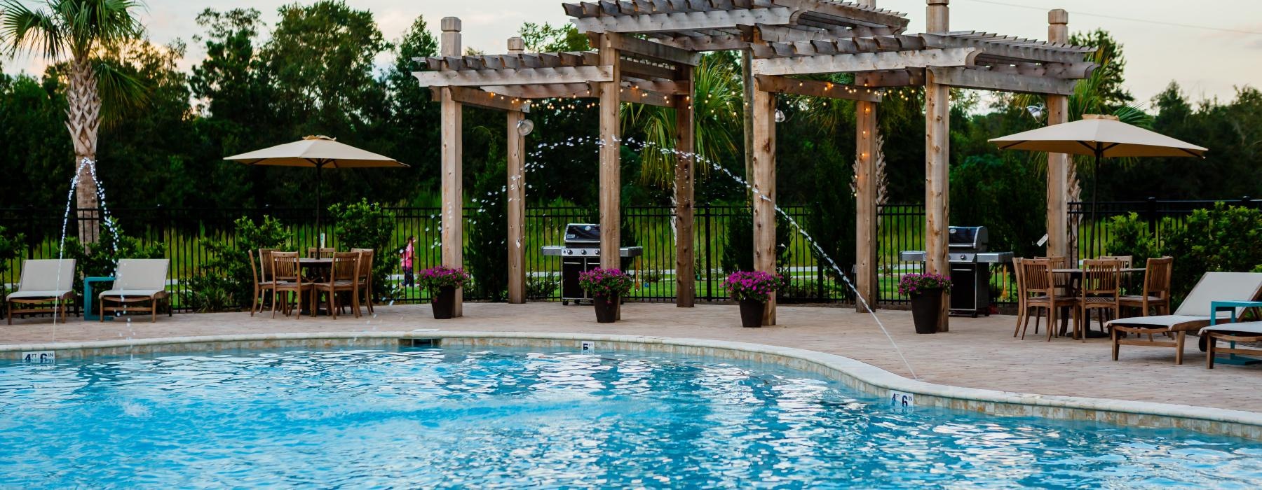 a pool with chairs and umbrellas by a gazebo