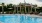 a pool with chairs and umbrellas by a gazebo