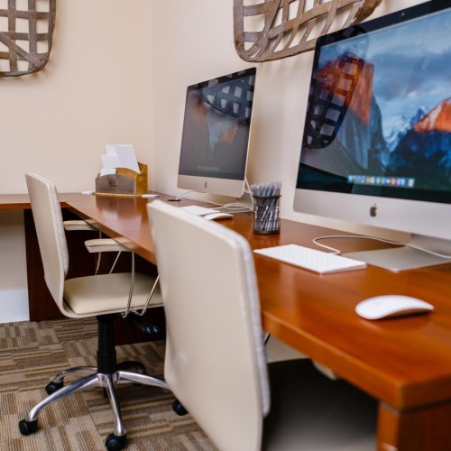 a desk with a computer and chairs